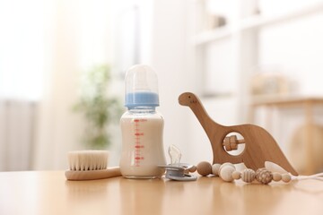 Bottle with milk and baby accessories on table indoors