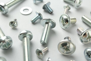 Many different metal bolts on light grey background, closeup. Hardware tool