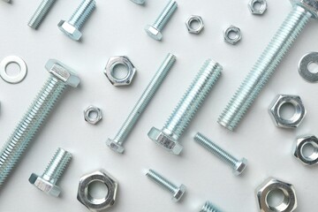 Metal bolts and nuts on white background, flat lay