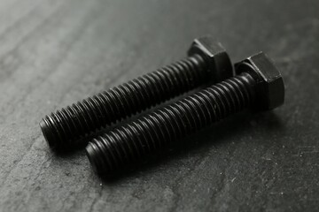Two metal bolts on black table, closeup