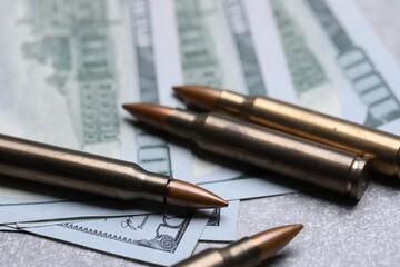 Bullets and dollars on grey table, closeup