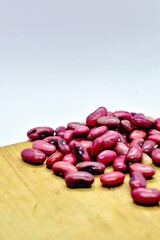 Close-up of fresh red kidney beans scattered on a wooden board, showcasing their natural color, smooth texture, and organic detail. beans are rich in protein, fiber, and essential nutrients