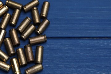 Obraz premium Many metal bullets on blue wooden table, flat lay. Space for text