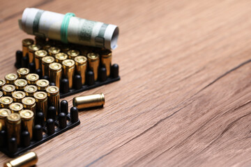 Bullets and dollars on wooden table, closeup. Space for text