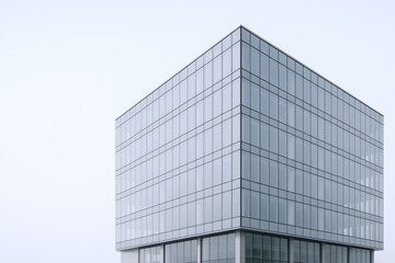 Modern Office Building Exterior Featuring Glass Windows and Geometric Design Against a Neutral Sky