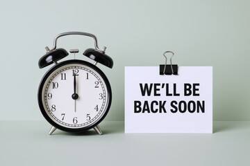 Vintage Alarm Clock Displaying Twelve O'Clock Next to Announcement Card on Pale Green Background