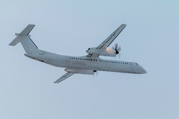 White passenger turboprop airplane flying in the air