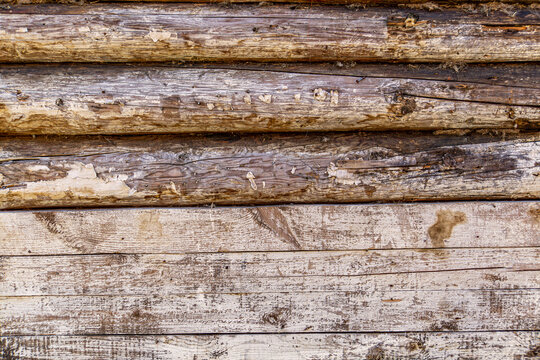 Close up of weathered wooden logs reveals cracked, aged surfaces with peeling paint. Texture highlights natural decay, wood grain, and rustic character, emphasizing aged construction materials. - Powered by Adobe