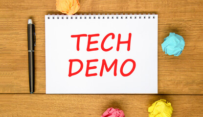 Fototapeta premium Tech demo symbol. Concept word Tech demo on beautiful white note. Black pen, colored paper. Beautiful wooden background. Business tech demo concept. Copy space.