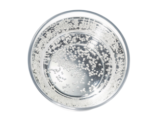 Effervescent circular bubbles rising in sparkling clear water in glass viewed from above and eye level