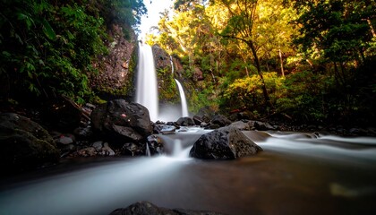 A tranquil waterfall cascade, flowing over dark rocks, framed by lush, vibrant greenery in a serene natural setting.