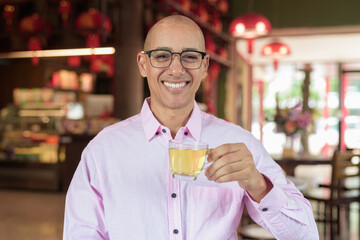 Bald Hispanic man wearing pink casual business shirt and eyeglasses in Chinese style tea house