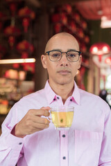 Bald Hispanic man wearing pink casual business shirt and eyeglasses in Chinese style tea house