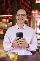Bald Hispanic man wearing pink casual business shirt and eyeglasses in Chinese style tea house