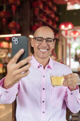 Bald Hispanic man wearing pink casual business shirt and eyeglasses in Chinese style tea house
