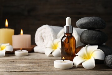 Composition with cosmetic product and spa stones on wooden table, closeup