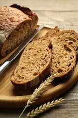 Pieces of fresh bread, spikes and knife on wooden table, closeup
