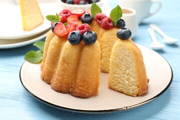 Tasty Bundt cake with berries and mint on light blue wooden table, closeup