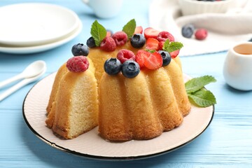 Tasty Bundt cake with berries, honey and mint on light blue wooden table, closeup