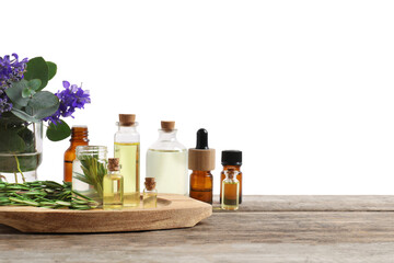 Bottles of essential oils and different plants on wooden table against white background