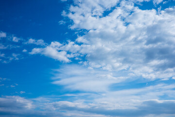 Obraz premium A photorealistic image of a blue sky with white clouds, showcasing a vast expanse of clear blue sky with scattered white clouds of various shapes and sizes. 