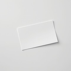 Blank white business card lying on a clean light gray surface with subtle shadow and soft lighting