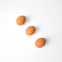 Three brown eggs arranged diagonally on a clean white background with ample copy space. Ideal for recipe blogs, menu design, nutrition content, or product packaging.