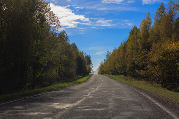 Autumn landscape and sunny evening, orange road and highway, asphalt and roadside.