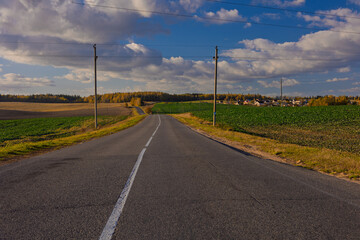 Autumn landscape and sunny evening, orange road and highway, asphalt and roadside.