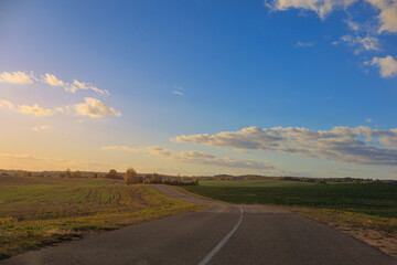 Autumn landscape and sunny evening, orange road and highway, asphalt and roadside.