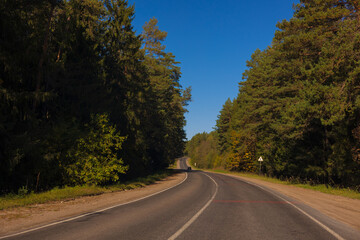 Autumn landscape and sunny evening, orange road and highway, asphalt and roadside.