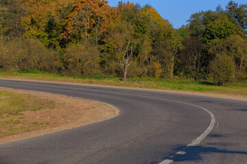 Autumn landscape and sunny evening, orange road and highway, asphalt and roadside.