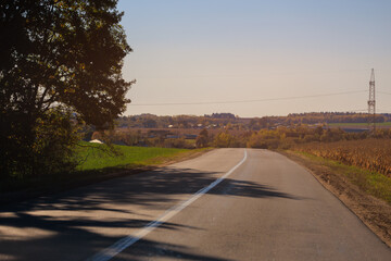 Autumn landscape and sunny evening, orange road and highway, asphalt and roadside.