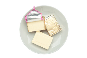 Processed cheese in foil on grey plate isolated on white background