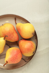 Fresh pear fruit on plate on light grey background. Vertical photo