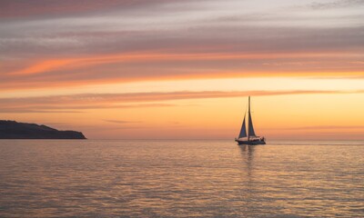 Fototapeta premium Sailboat at sunset over calm water
