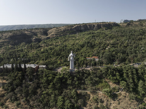 Aerial view of the majestic Kartlis Deda statue stands sentinel atop Sololaki Hill, overlooking the city's sprawling greenery and distant skyline, Tbilisi, Tbilisi, Georgia.