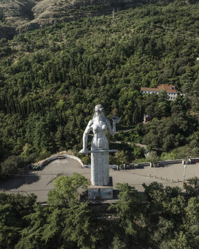 Aerial view of the Kartlis Deda statue standing tall against the backdrop of lush green mountains, a striking contrast of stone and nature, Tbilisi, Tbilisi, Georgia.