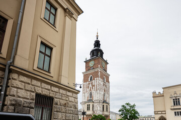 Fototapeta premium Historic street view in Krakow with clock tower and parked cars