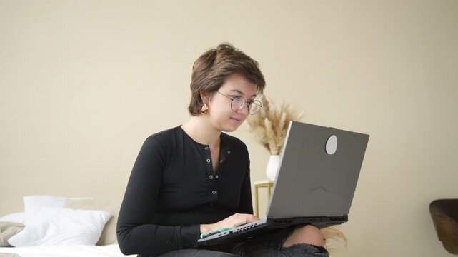 A young female blogger expresses authentic emotions while working on her daily routine - from focused laptop work to joyful phone moments. Perfect for modern lifestyle and digital nomad content