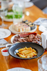 A sumptuous banquet is served on the table with meat dishes, accompanied by French fries, a variety of salads and snacks.