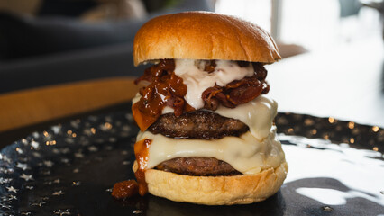 Massive gourmet burger with two juicy beef patties, overflowing melted cheese, crispy bacon, rich bacon mayo, and special sauce on a toasted brioche bun. Extreme food close-up