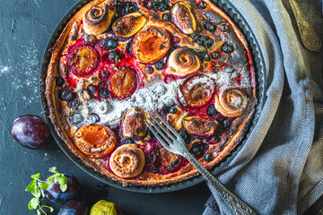 A tart or open pie with blueberries, figs, prunes and apricots in a baking dish on a gray background. Close-up. High quality photo
