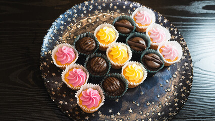 Beautiful chocolate and assorted cupcakes on an elegant plate, perfect for parties or family gatherings. Soft lighting and shallow depth of field.