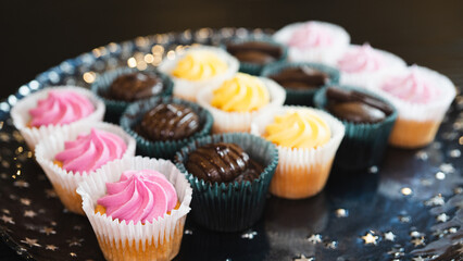 Beautiful chocolate and assorted cupcakes on an elegant plate, perfect for parties or family gatherings. Soft lighting and shallow depth of field.
