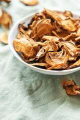 Dried mushrooms in a bowl resting on a green cloth