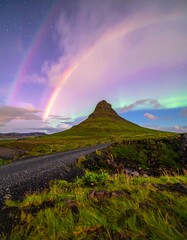 Double rainbow over mountain landscape at night