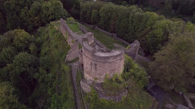 Low altitude drone orbit around the tower of Windeck Castle ruins in North Rhine-Westphalia, Germany, then side flight along the medieval stone walls in foggy historic atmosphere