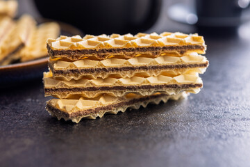 Sweet crispy wafers on black table.