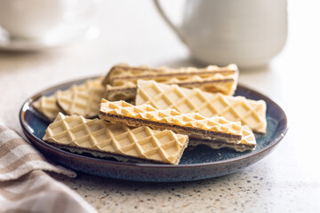 Sweet crispy wafers on plate on kitchen table.